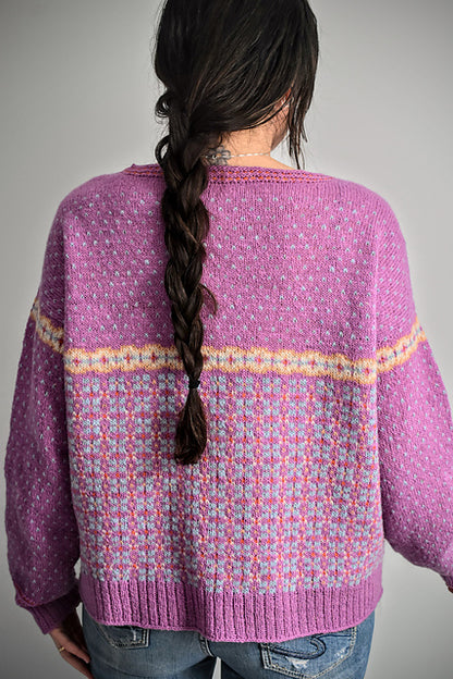 Person wearing a purple patterned sweater with a gray background